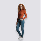 Celviroa rust orange long-sleeve zip-neck bodysuit made of polyester and spandex blend, worn by a woman with red curly hair and blue jeans.